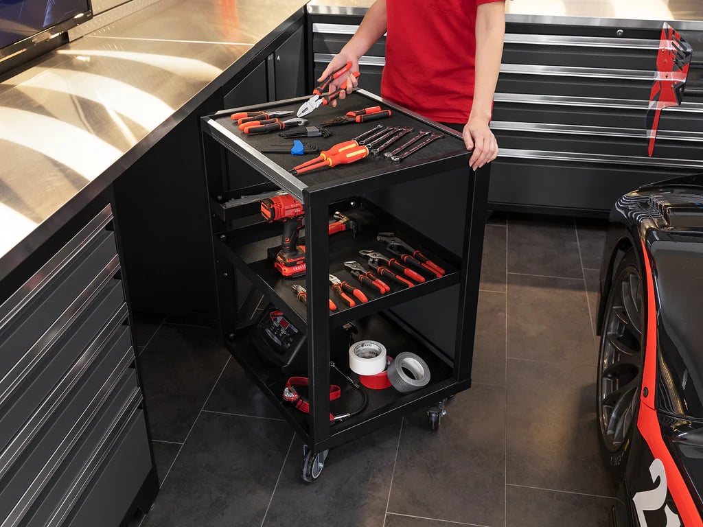 female mechanic moving rolling tool cart towards a car